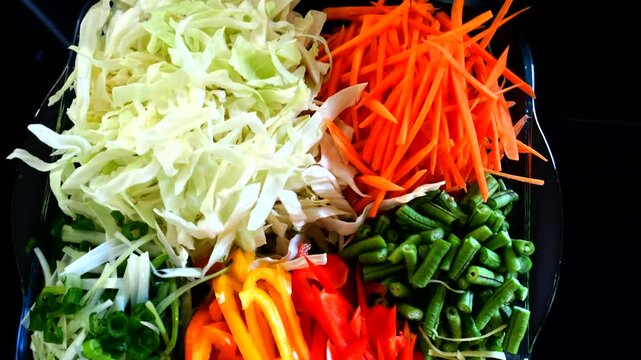 Freshly cut vegetables in a bowl featuring long beans, spring onions, peppers, and cabbage, showcasing a nutritious, plant-based mix for clean eating or cooking.