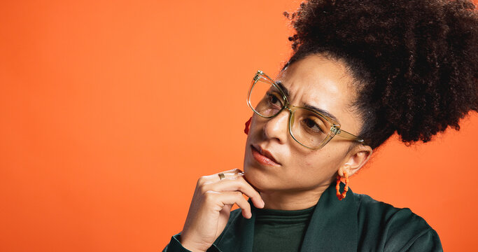Thinking, mockup and glasses with woman in studio for idea, fashion decision and reflection. Vision, wardrobe inspiration and brainstorming with person on orange background for solution and space - Powered by Adobe