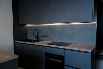 Contemporary kitchen with a black induction cooktop, built-in oven and lighting
