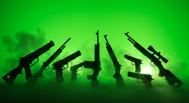 A silhouette of various types of firearms against a green background with smoke and dramatic lighting