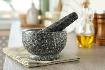 Stone mortar and pestle on wooden table in kitchen