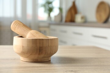 Mortar and pestle on wooden table in kitchen, closeup. Space for text