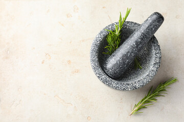 Stone mortar with rosemary and pestle on light table, top view. Space for text