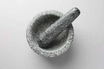 Stone mortar and pestle on light grey background, top view