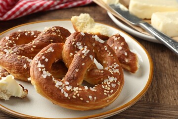 Tasty pretzels with salt and butter on wooden table, closeup