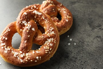 Tasty pretzels with salt on grey table, closeup. Space for text