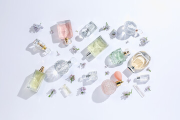 Luxury perfumes and beautiful lilac flowers on white background, flat lay