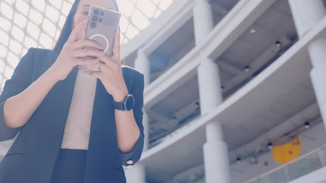 A woman is holding a cell phone in her hand. She is wearing a black jacket. The phone is a Samsung