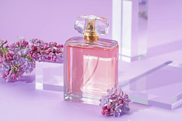 Stylish presentation of perfume bottle and lilac flowers on violet background, closeup