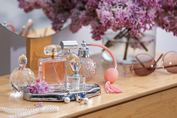 Bottles of perfumes, accessories and lilac flowers on wooden table