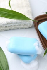 Soap bars with foam on white table, closeup