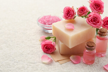 Soap bars, sea salt, essential oils and beautiful roses on beige table, closeup. Space for text