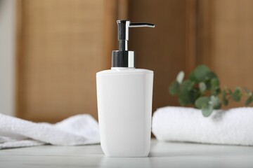 Liquid soap in bottle, towels and eucalyptus branch on white marble table indoors