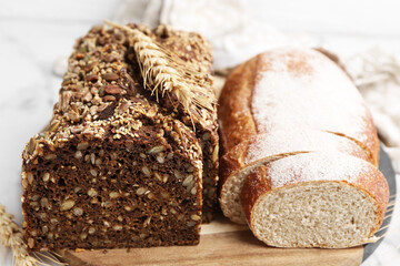 Freshly baked loaves of bread and spikes on white table, closeup