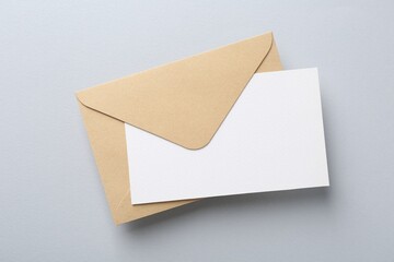 Blank invitation card and envelope on light grey background, top view
