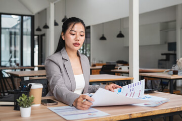 Businesswoman checking documents on stacked desk