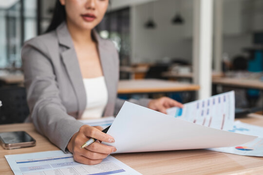 Businesswoman checking documents on stacked desk