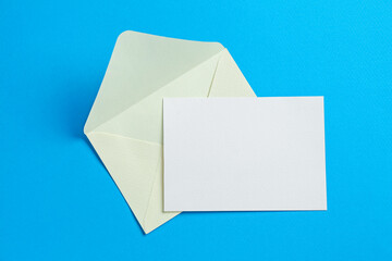 Blank invitation card and envelope on light blue background, top view. Space for design