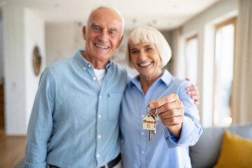 Obraz premium Happy elderly couple showing house keys in new home.