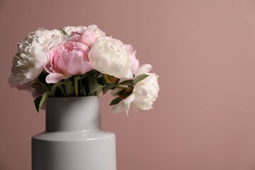Beautiful peonies in vase near pink wall, closeup. Space for text