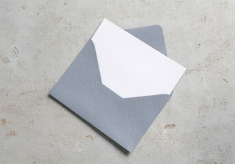 Blank invitation card and envelope on light grey table, top view. Space for design