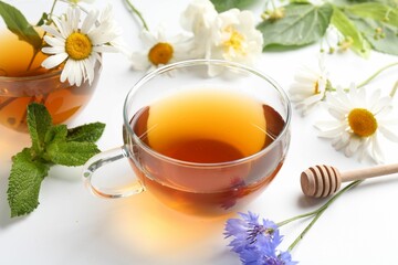 Aromatic herbal tea in glass cups, different flowers and mint on white background, closeup
