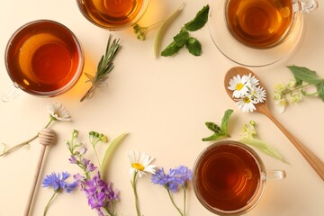 Aromatic herbal tea in glass cups and different flowers on beige background, flat lay. Space for...