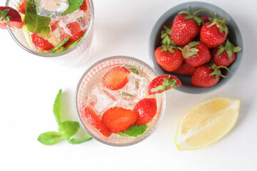 Tasty refreshing drink with strawberries, lemon and mint on white table, flat lay