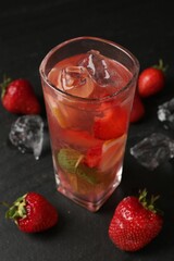 Refreshing drink with strawberries and ice on dark table, closeup