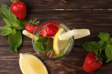 Refreshing drink with strawberries, lemon and mint on wooden table, flat lay