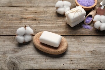 Soap bars, cosmetic products and cotton flowers on wooden table, above view