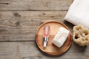 Soap bars, cosmetic products, towel and loofah sponge on wooden table, flat lay. Space for text