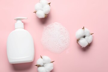 Flat lay composition with bottle of liquid soap and cotton flowers on pink background