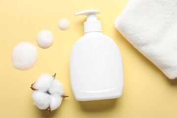 Flat lay composition with bottle of liquid soap and cotton flower on yellow background