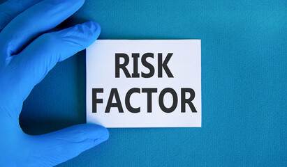 Risk factor symbol. Concept words Risk factor on beautiful white card. Doctor's hand in blue...
