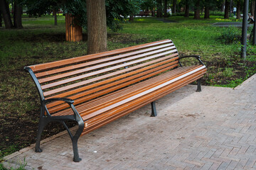 A beautifully crafted wooden bench is placed in a serene park, surrounded by lush green trees in the background, offering a perfect spot for relaxation and enjoying natures beauty