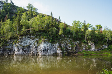 A serene lake is nestled in the midst of lush trees and rugged rocks, creating a picturesque scene in the heart of a beautiful forest, showcasing natures endless beauty and tranquility