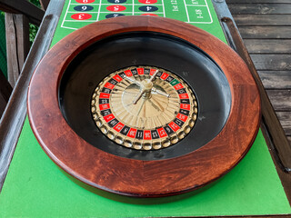 A beautifully crafted wooden roulette wheel is prominently placed on a vibrant green mat, ready to engage players in exciting games of chance and strategy, reminiscent of lively casinos