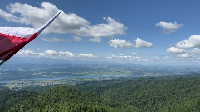 Polish flag in the wind, view of Polish mountains and valleys in the background.