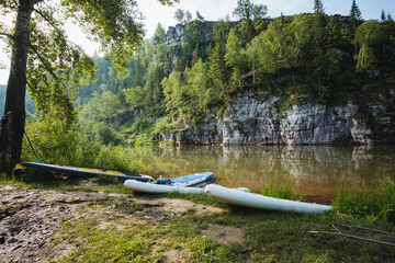 A couple of colorful kayaks are sitting peacefully on the sandy shore of a beautiful river, awaiting adventurous paddlers to enjoy a captivating journey on the water surface