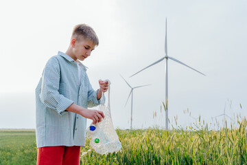 Teenager sorting plastic bottles in eco bag near wind turbines