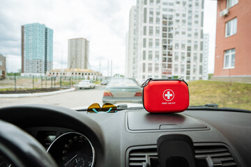 A bright red first aid kit is currently resting prominently on the dashboard of a car, ready for...