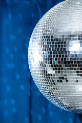a large disco ball casts a glow against the blue curtains.