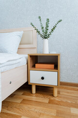 In the cozy ambiance of a bedroom, there is a nightstand positioned right next to a comfortable...
