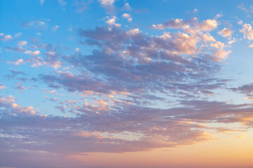 sunrise with light cirrus clouds in soft orange and pink tones, with the sun on the horizon