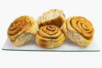 Homemade cinnamon rolls on a glass plate, close-up with white background