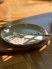 Close-up of empty dessert plate with fork and berry stains in cozy cafe
