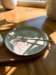 Fork on empty plate with berry stains in sunny cafe corner