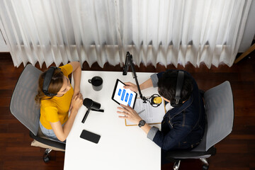 Top view of smiling radio influencer hosts wearing headphone with channel social media online live...