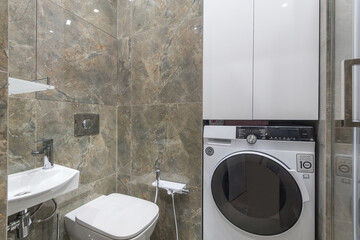 Compact modern laundry area featuring a washing machine and sink in a stylish bathroom design with...
